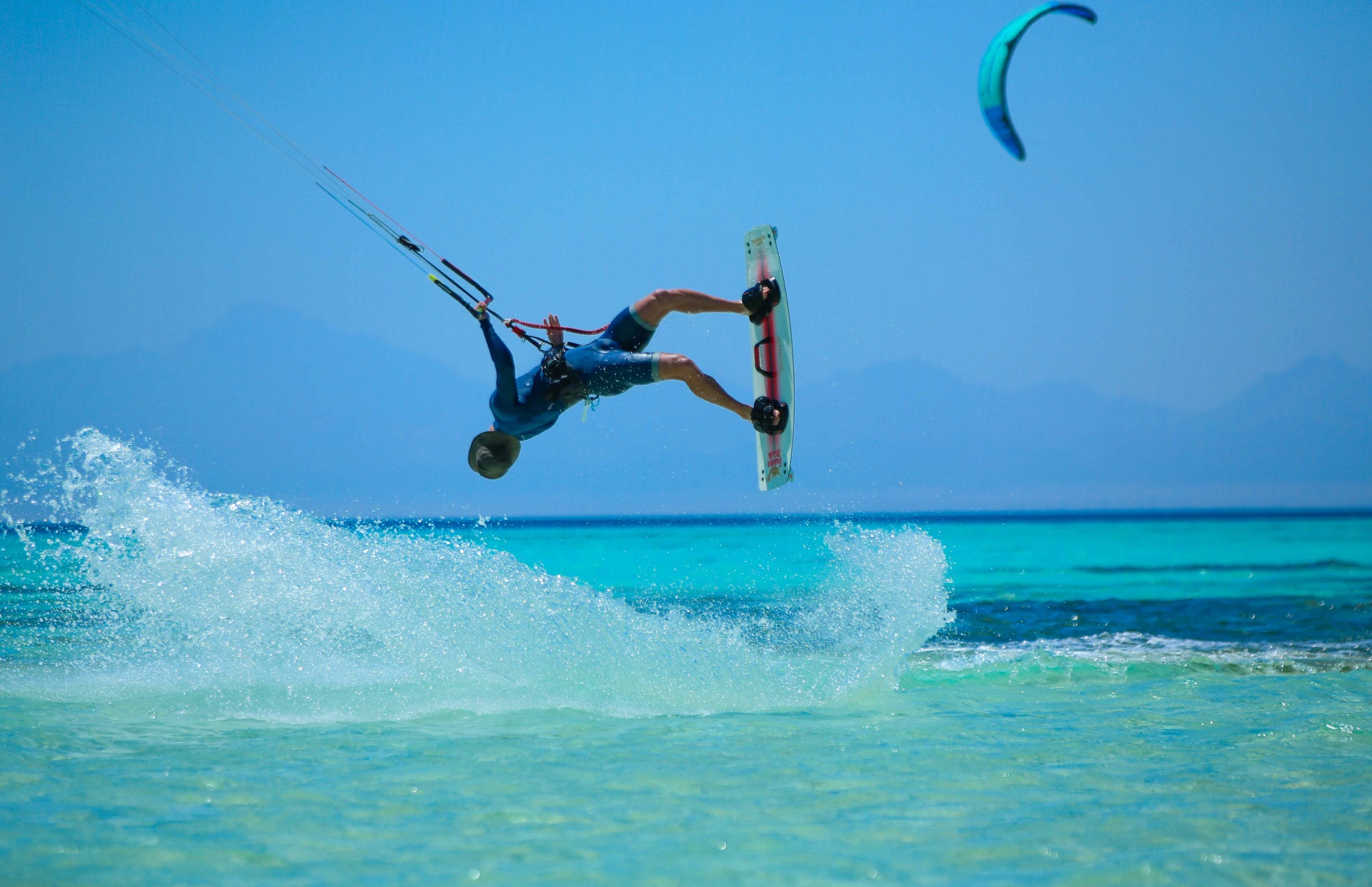 Kitesurfer launching a big air jump over turquoise Red Sea water