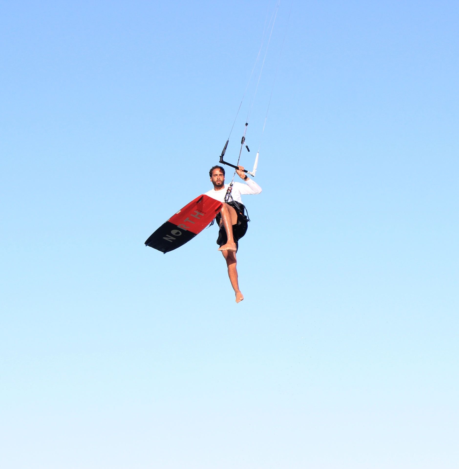Kitesurfer boosting high against blue sky