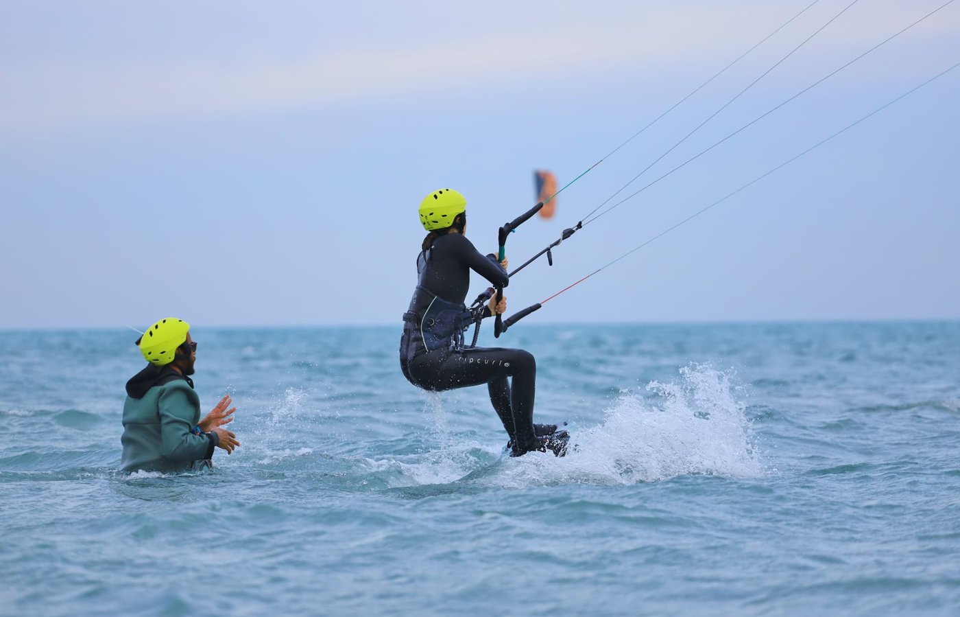 Instructor guiding a beginner kitesurfer in a helmet across the shallow El Gouna lagoon