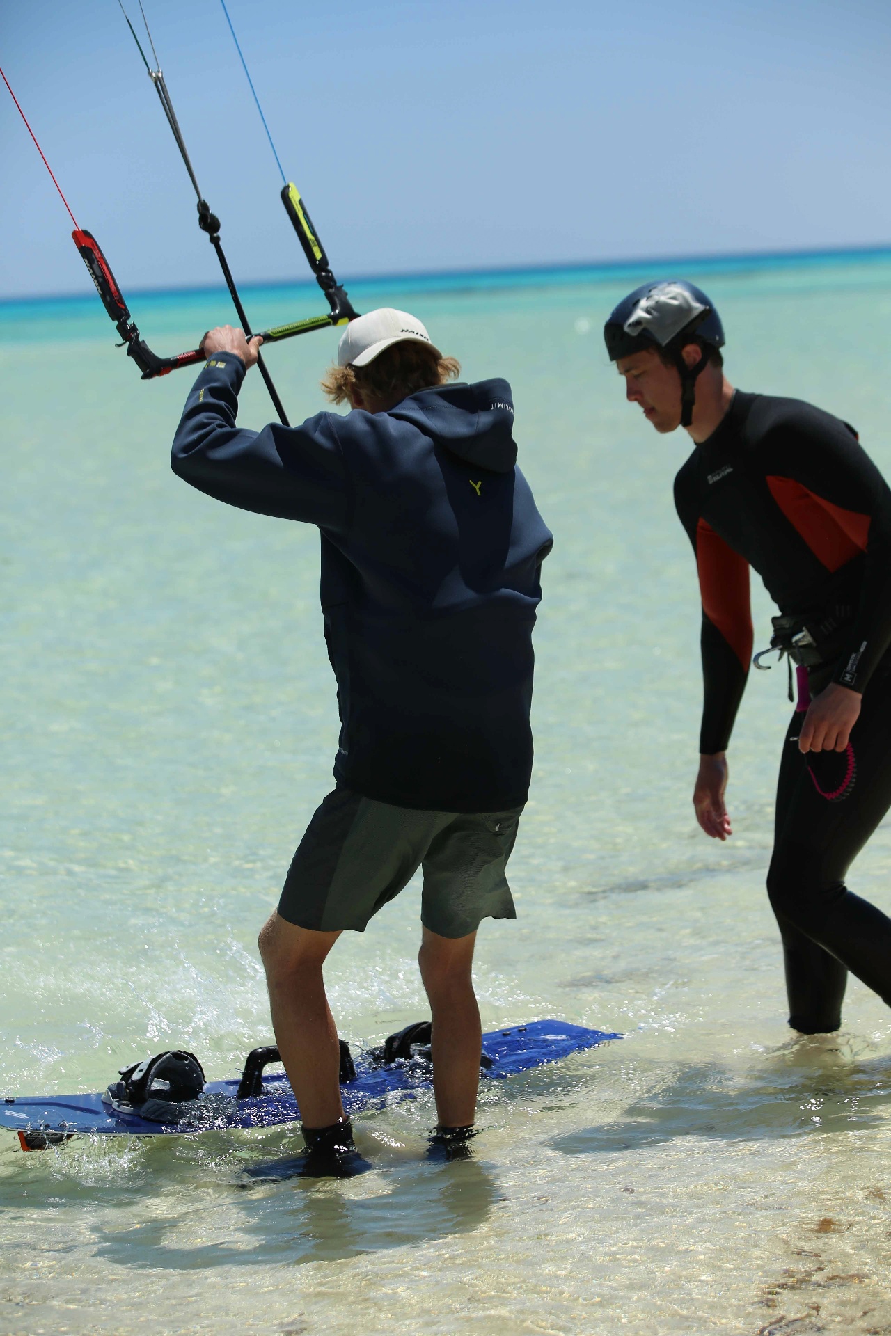 Instructor guiding a student on a board in the shallow lagoon