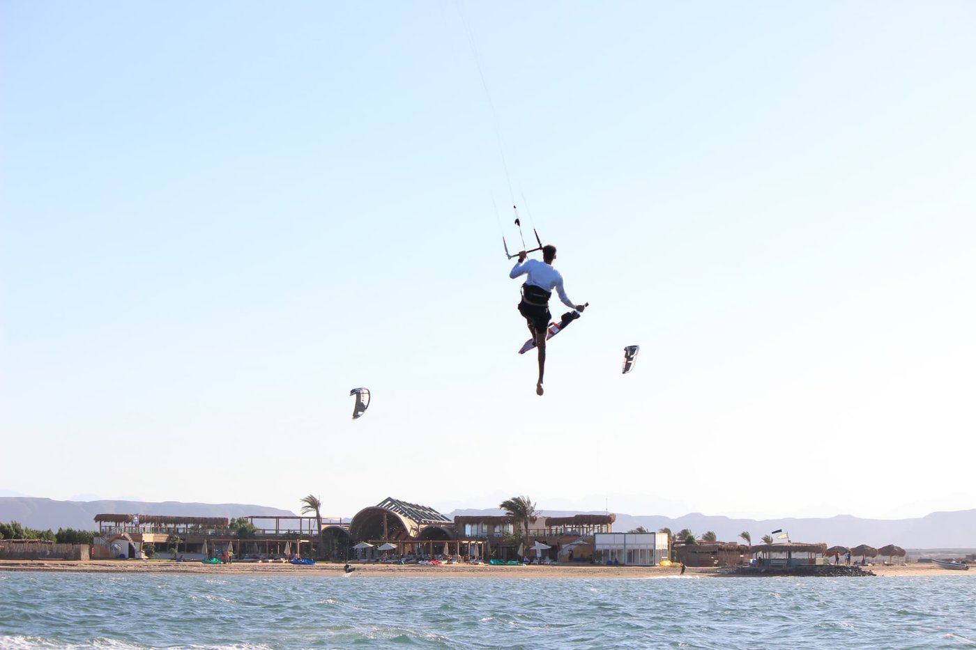 Kitesurfer jumping high above the Red Sea with the El Gouna shoreline behind