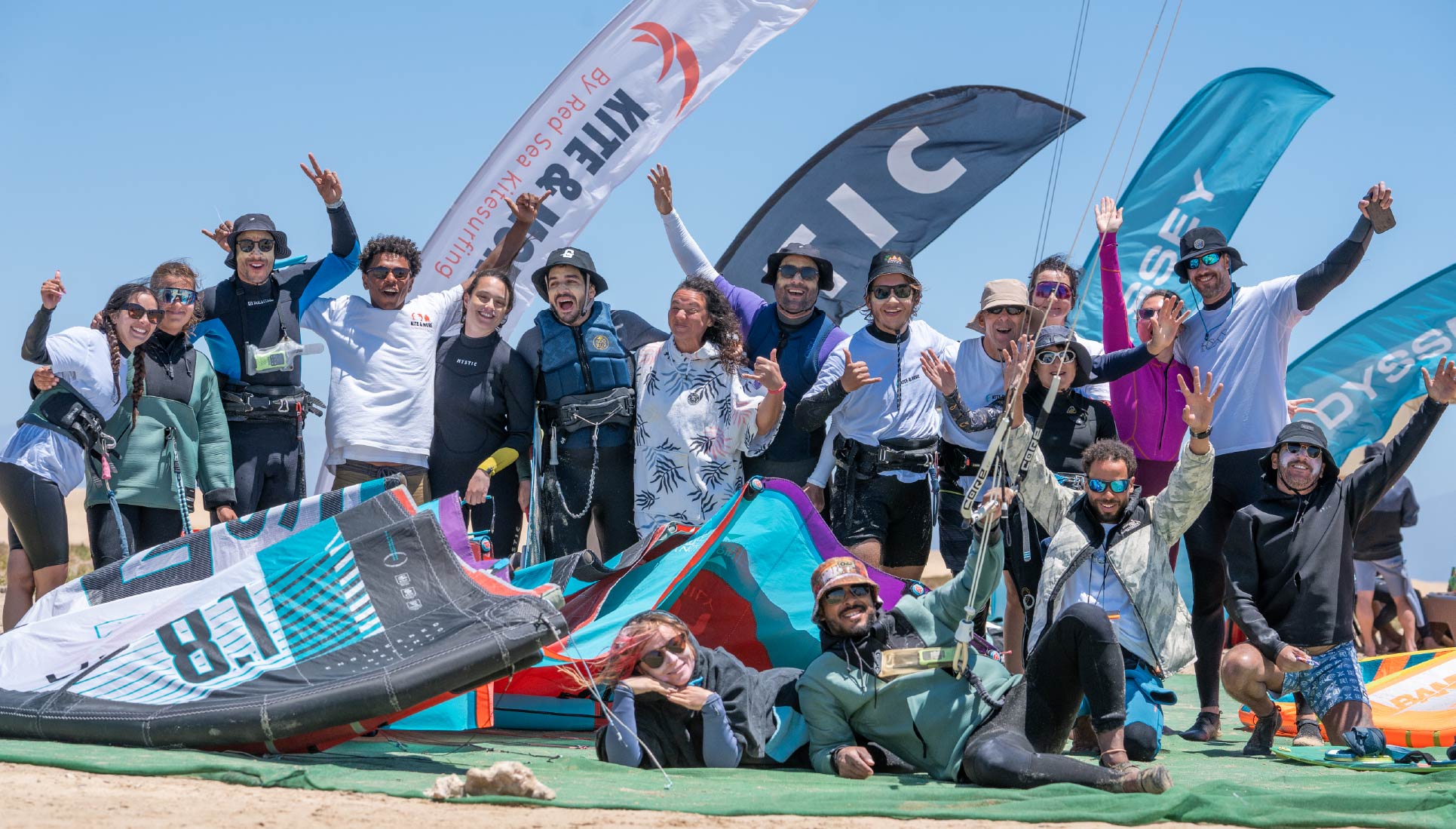 Red Sea Kitesurfing crew celebrating together on the beach with kites and flags