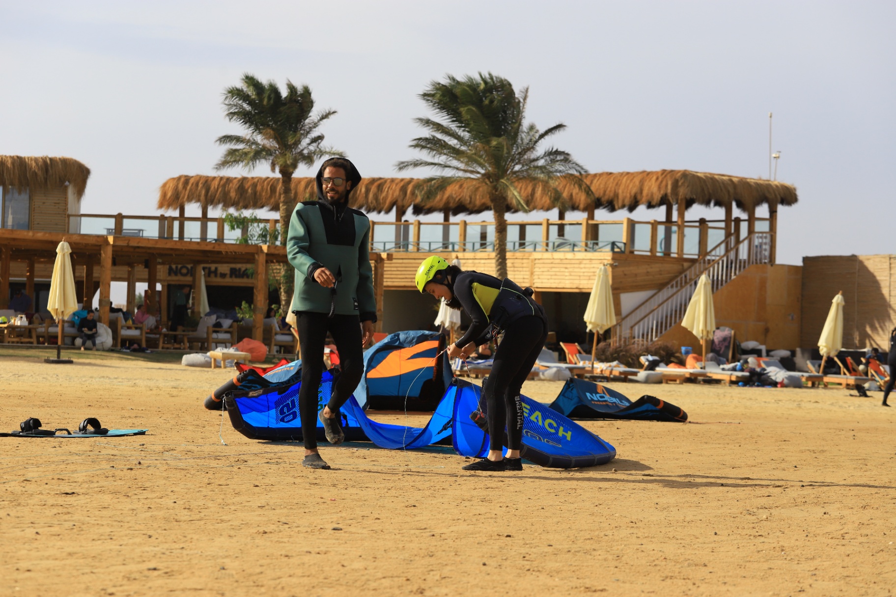 Instructor and student setting up a kite on the beach