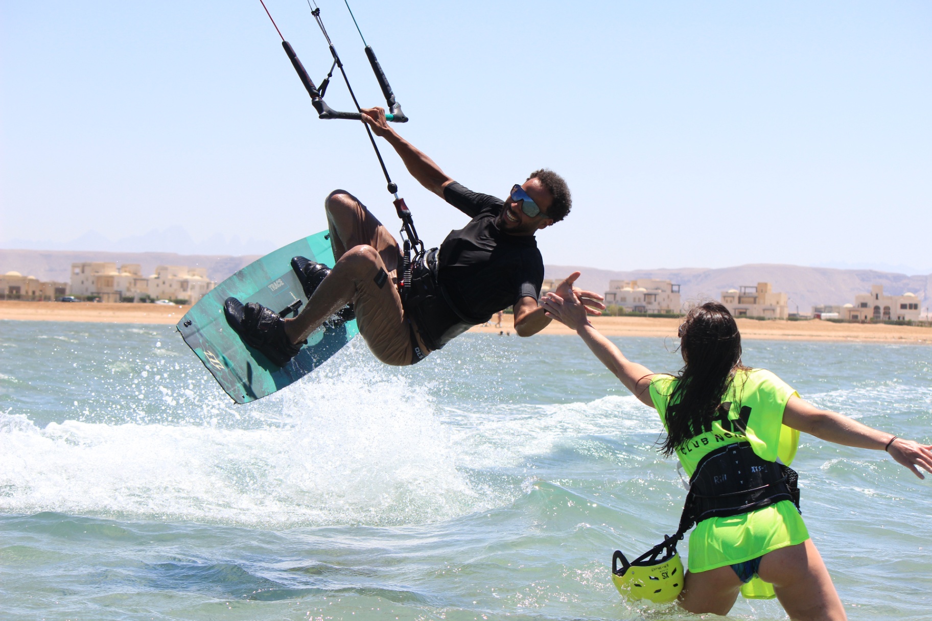 Kitesurfer jumping and high-fiving student