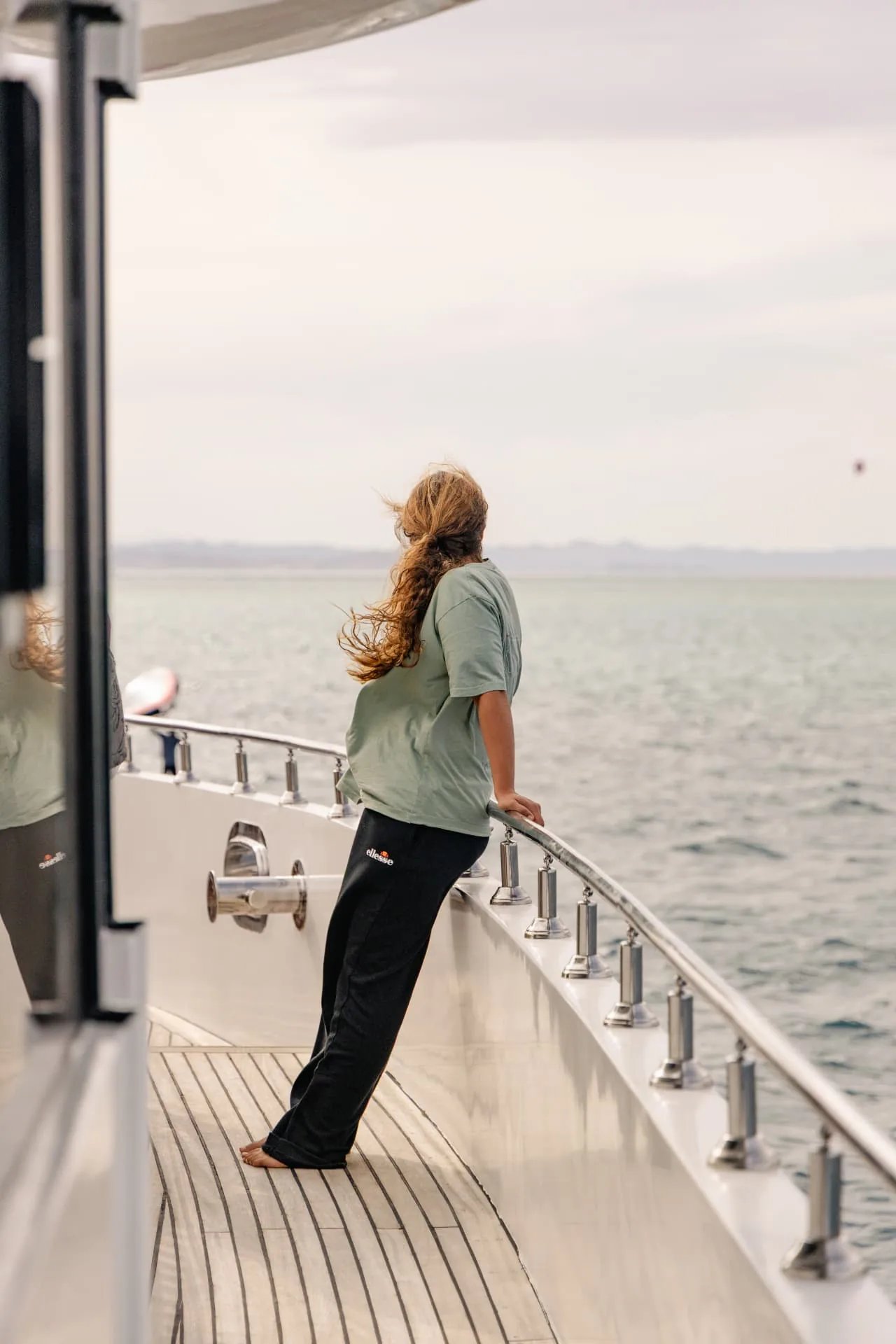 Guest looking out to sea from the yacht's teak deck