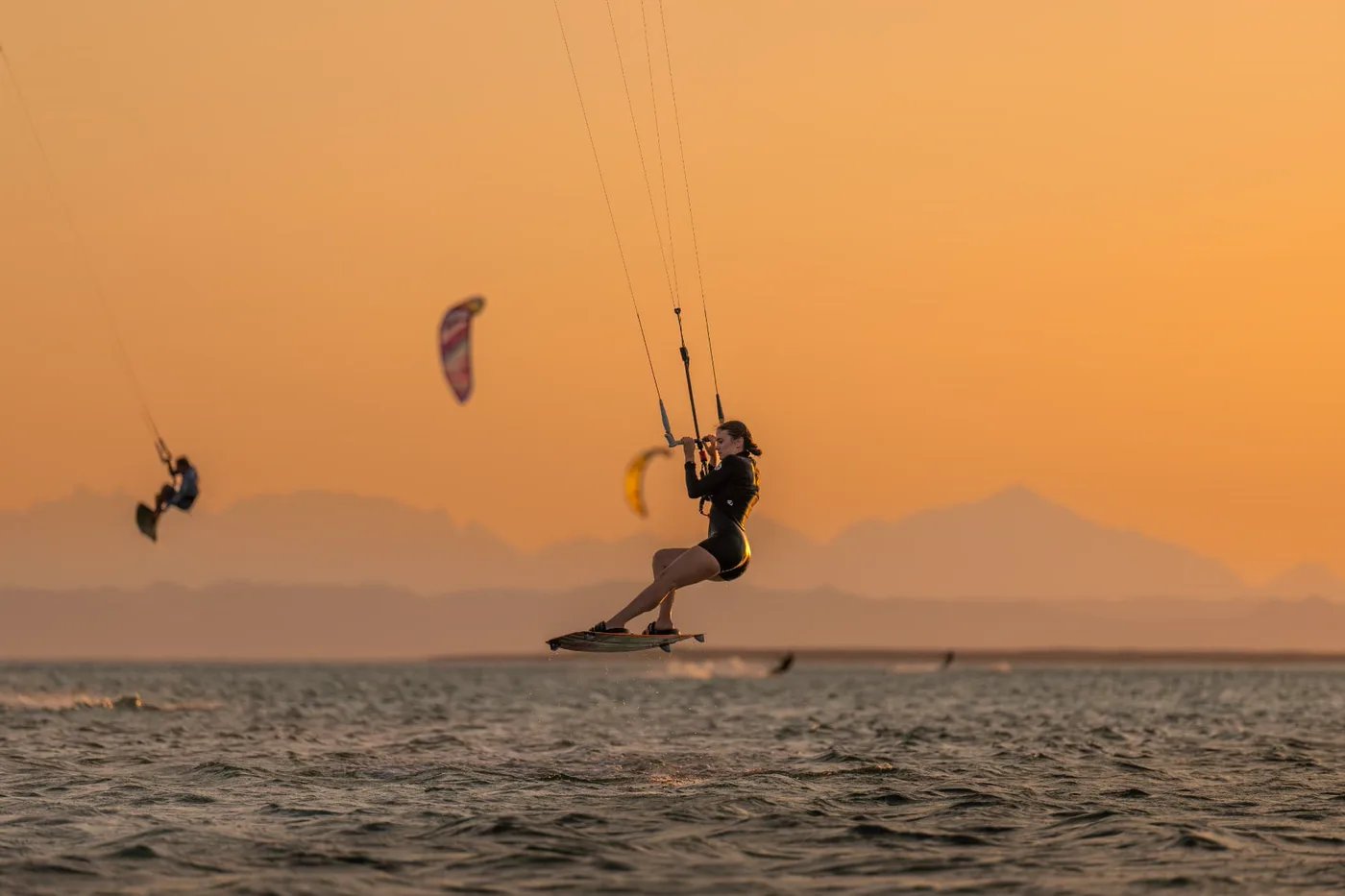 Kitesurfer jumping high over the sea at sunset during a Red Sea kite safari, mountains on the horizon