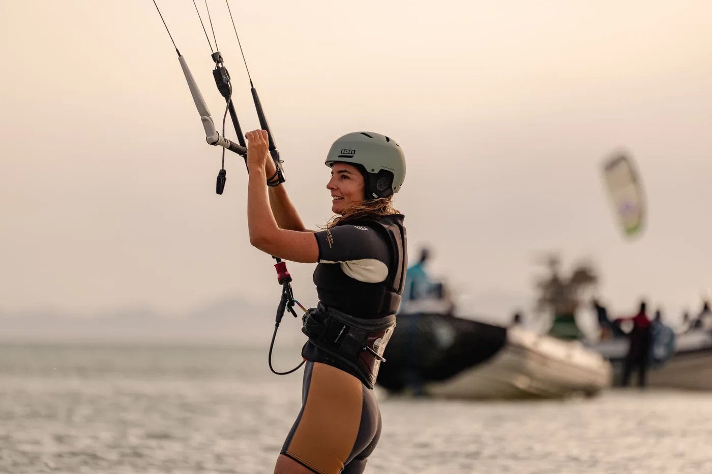 Smiling guest ready to ride, standing in shallow water with her kite lines