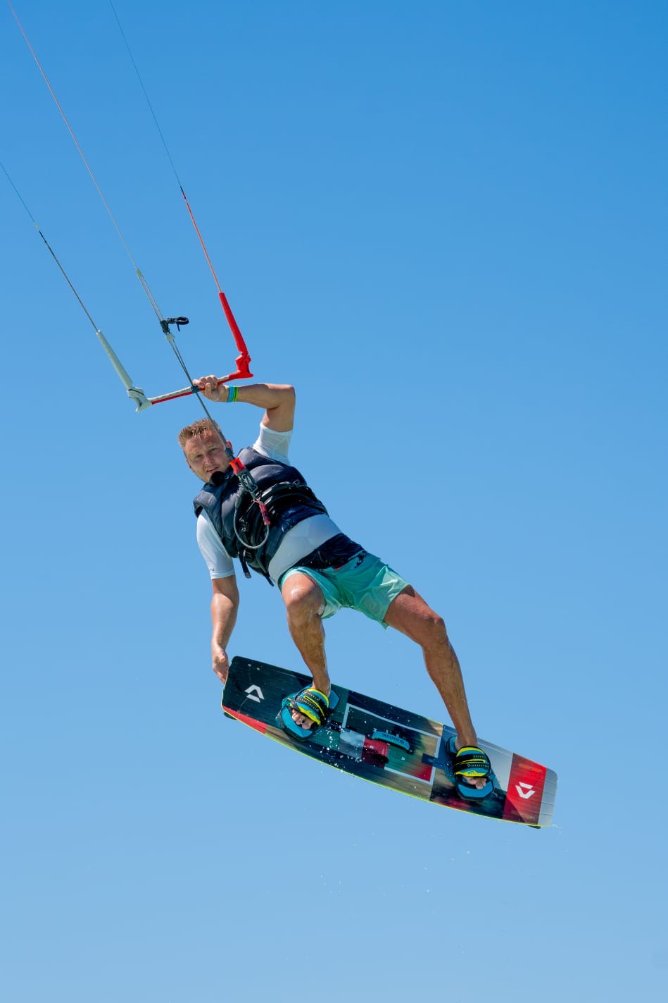 Kiter boosting a huge air against a clear blue sky