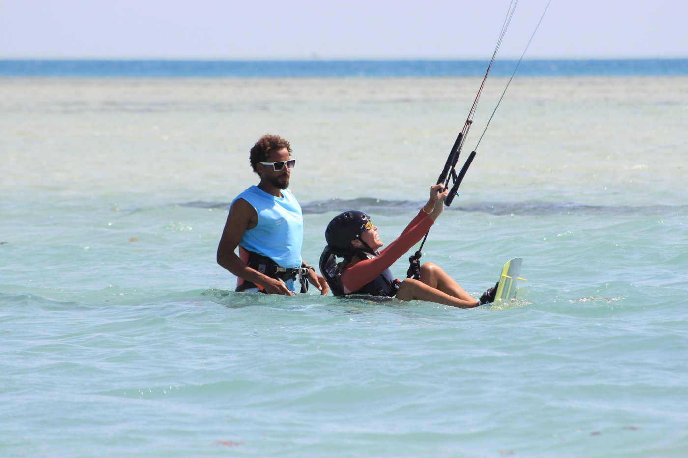 Instructor coaching a rider on the board in flat Red Sea water
