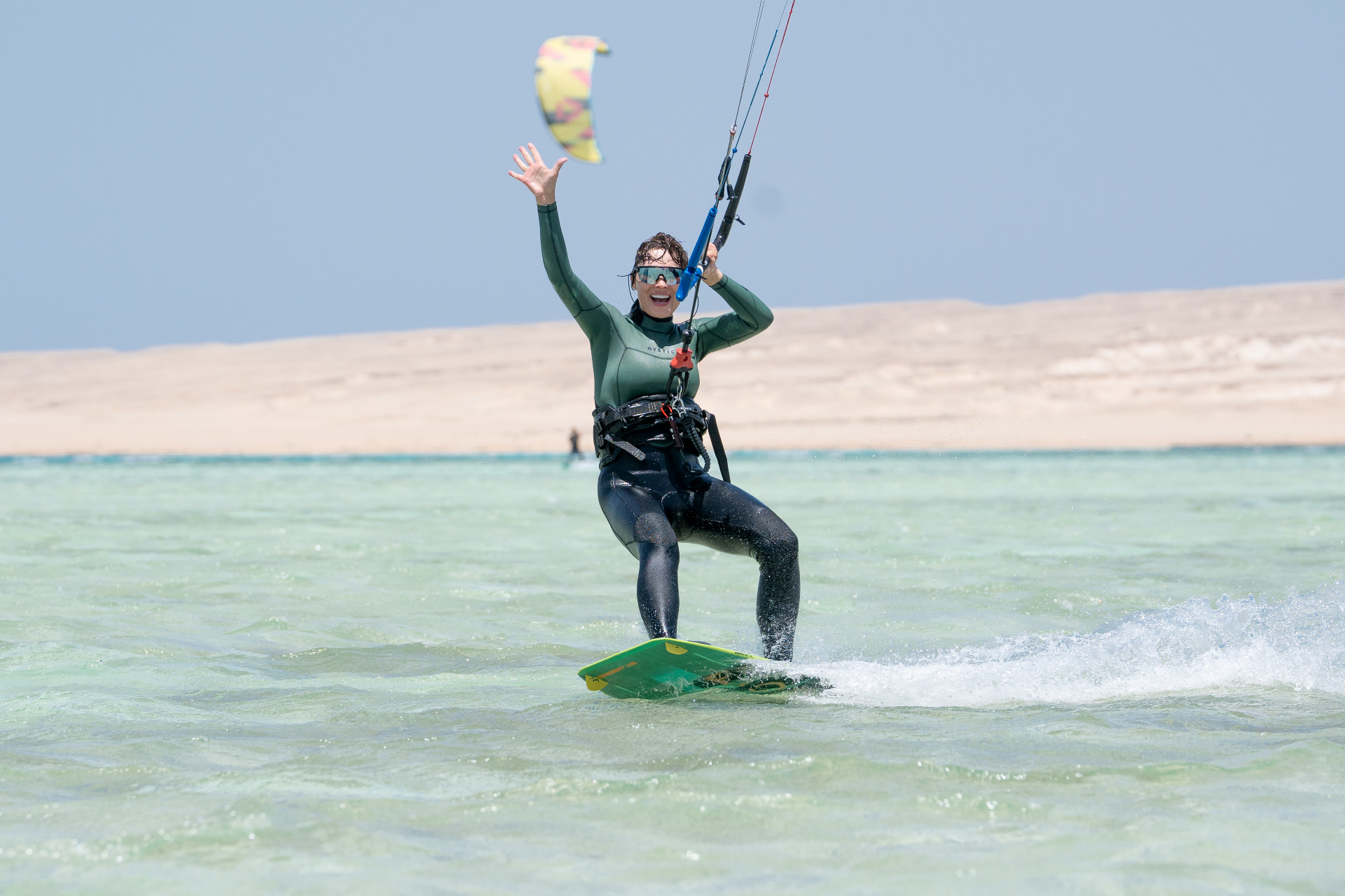 Smiling kitesurfer waving while riding the Red Sea lagoon