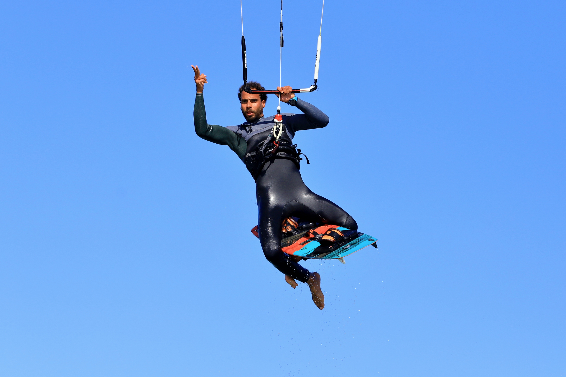 Kitesurfer boosting high into a blue sky
