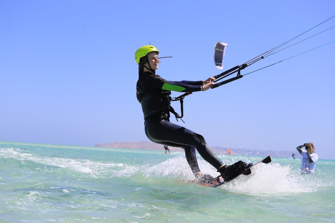 Kitesurfer wearing a helmet riding across the turquoise Red Sea