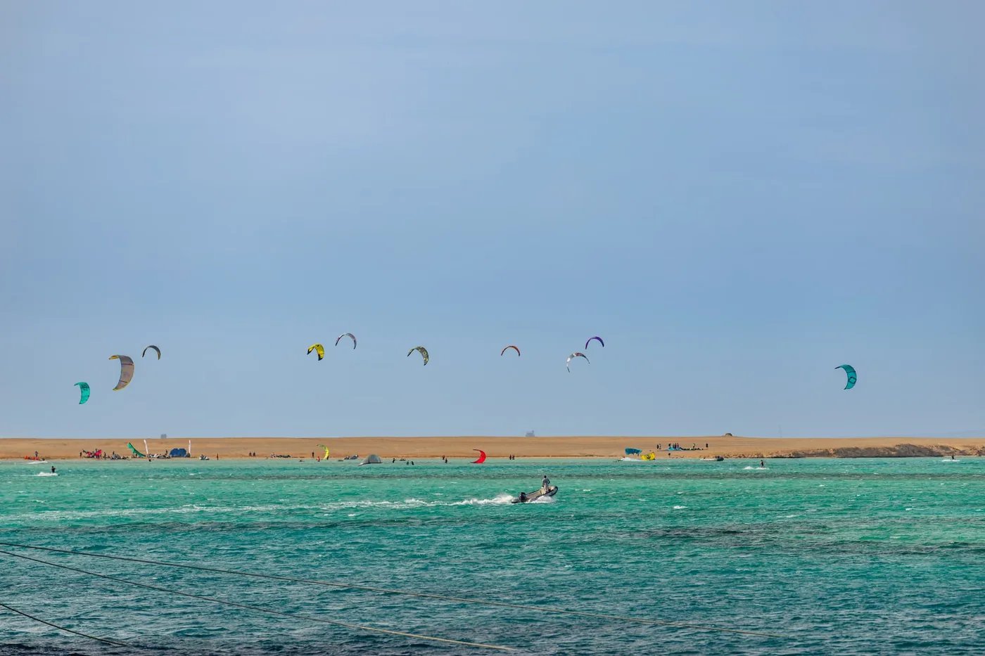 Turquoise Red Sea lagoon dotted with kites and a support boat