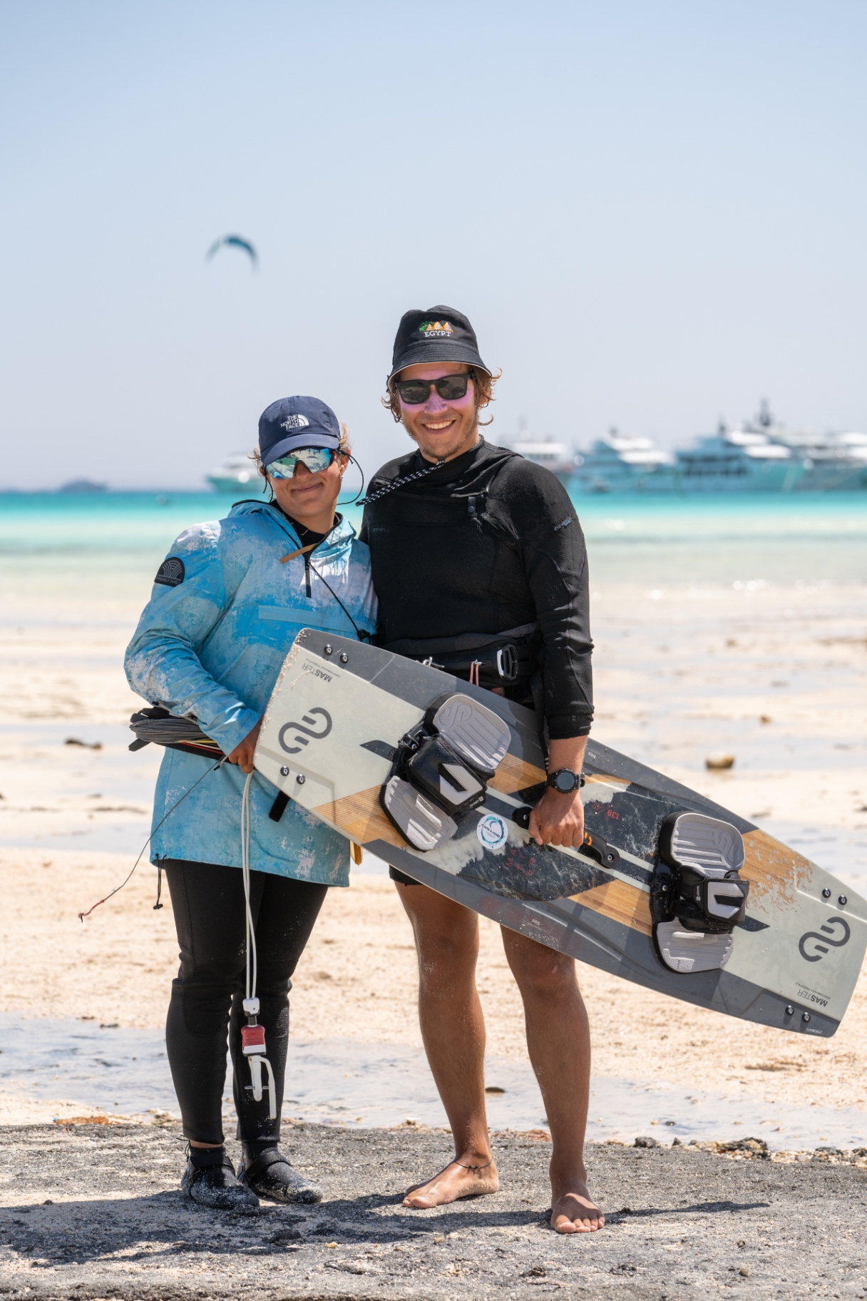 Instructor and student posing with a kiteboard in front of yachts