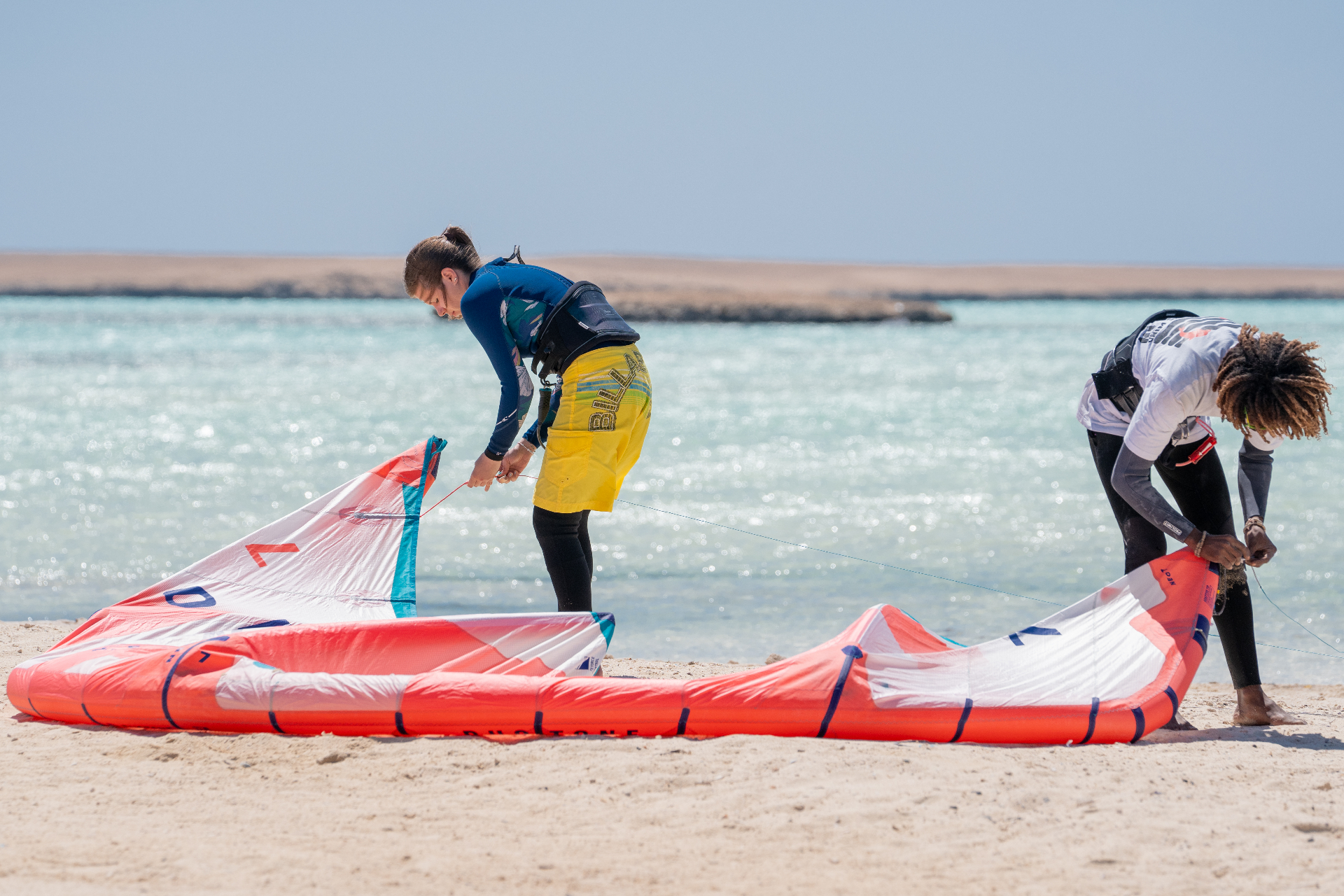 Two riders preparing a kite on the beach