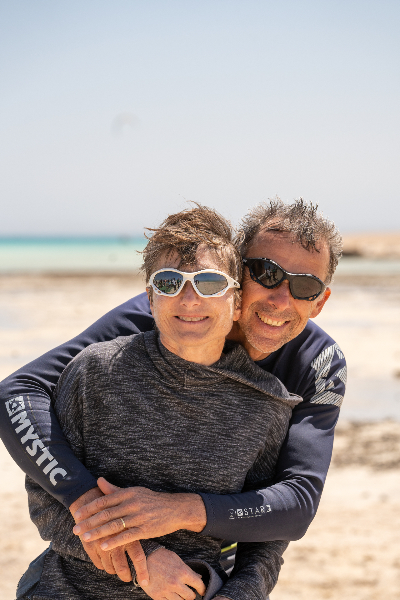 Couple sharing a hug on the beach after kiting